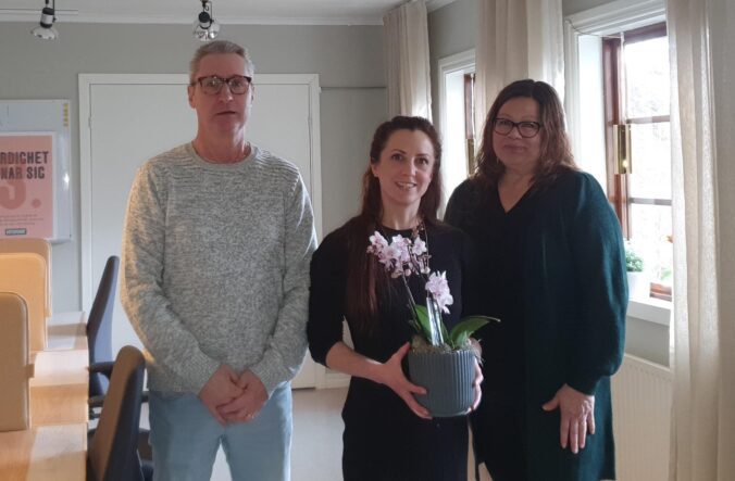 Thomas och Niina överlämnar en blomma till Katharina Sandberg